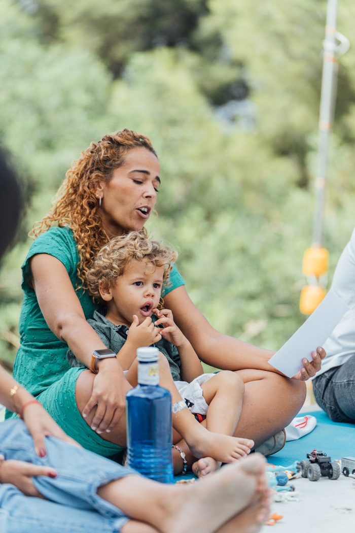 A woman and a small child sitting outside at a YOUNG gathering
