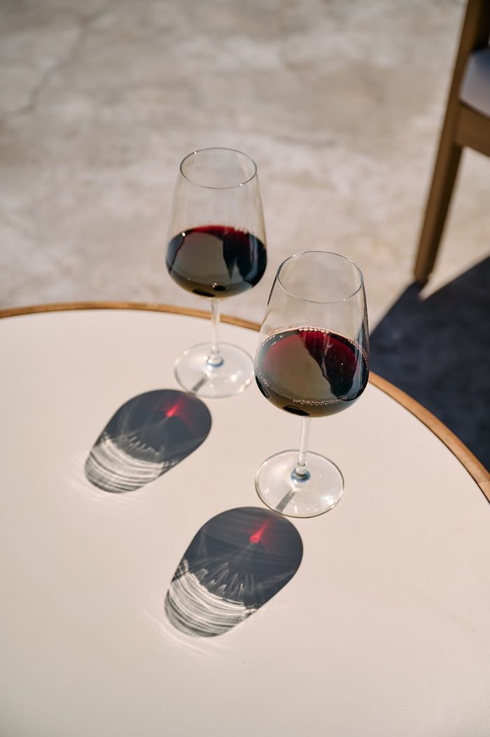 Two glasses of red wine on a sunlit table