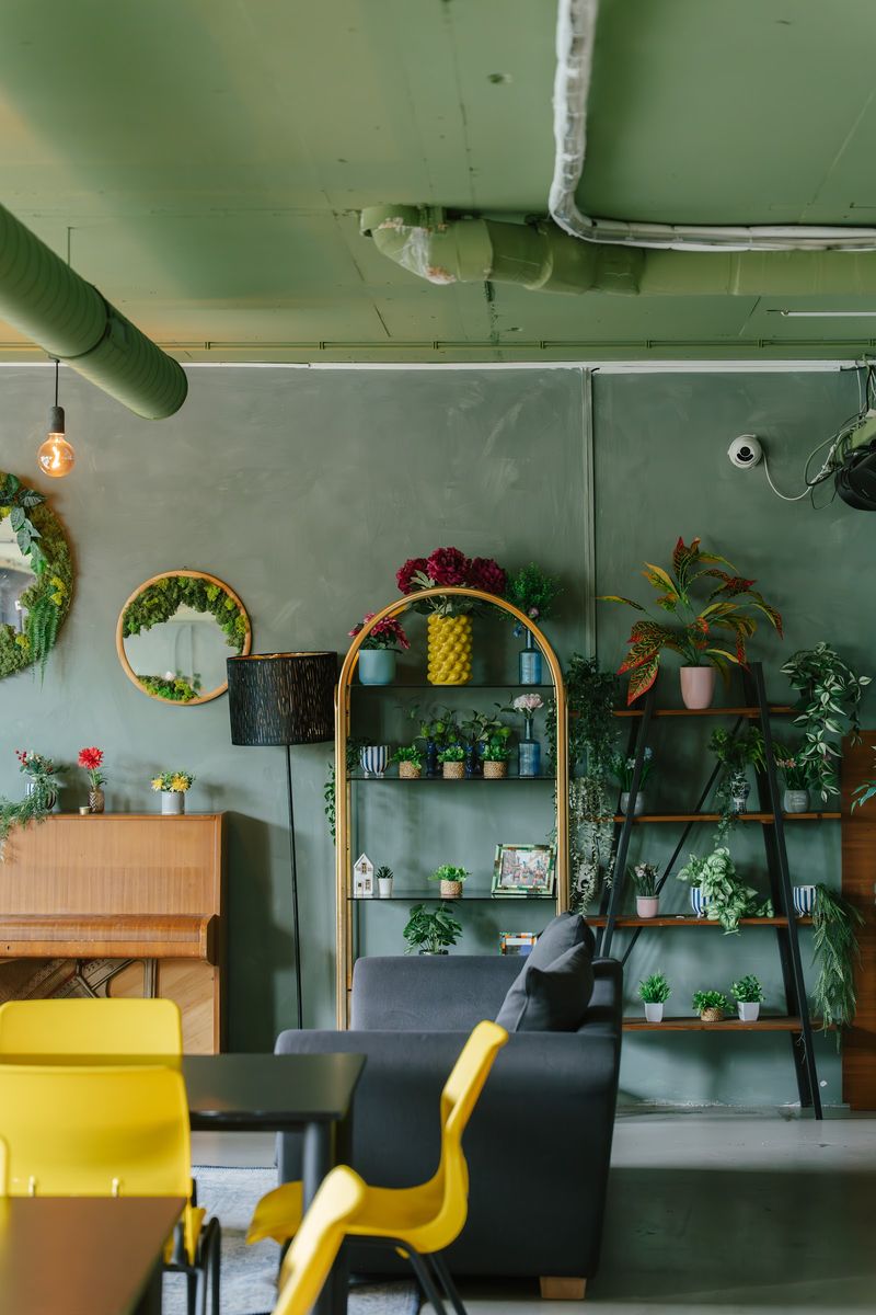 A YOUNG.Workspaces lounge, plants and a piano along a green wall